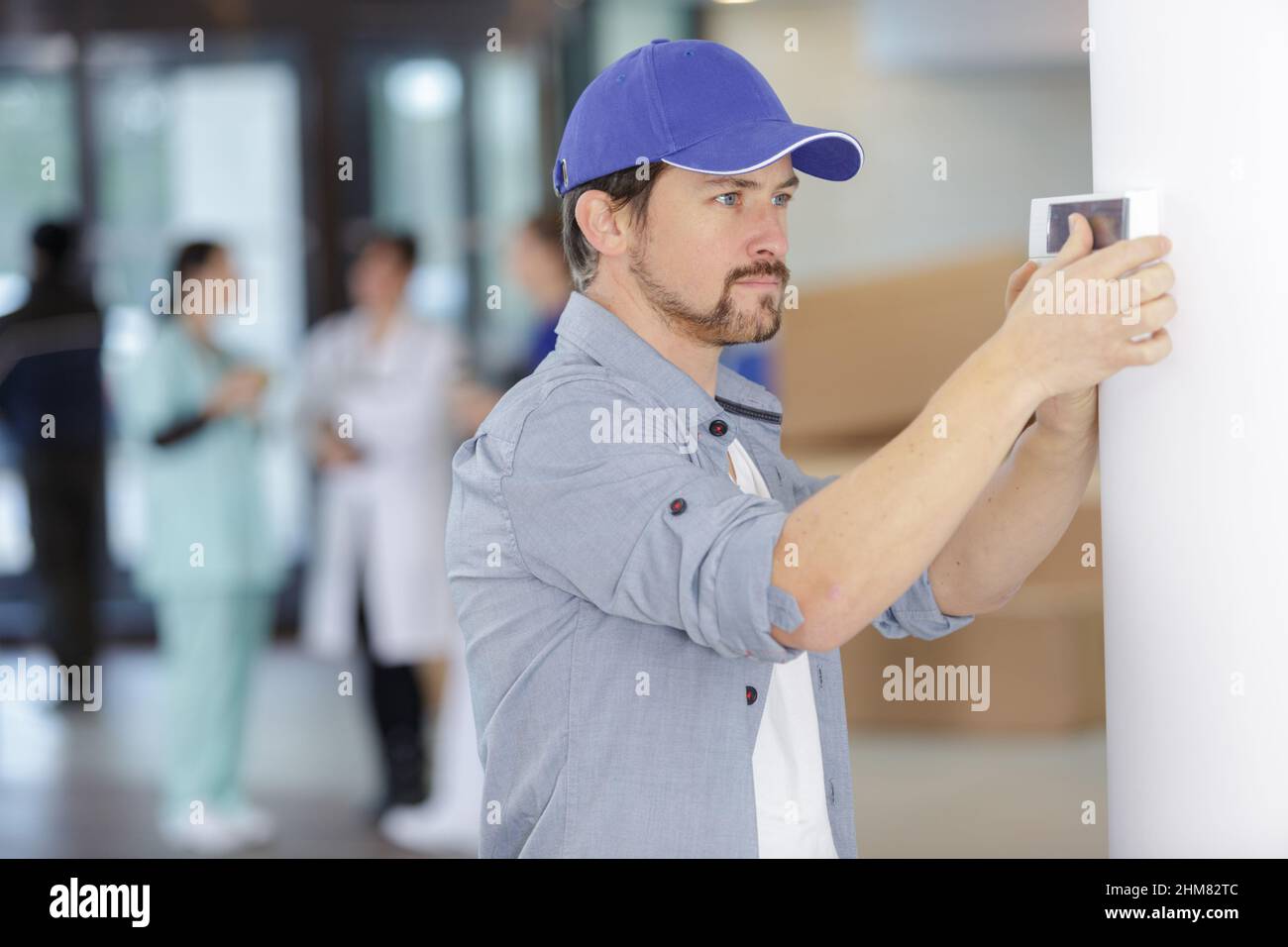 a male worker installing thermostat Stock Photo