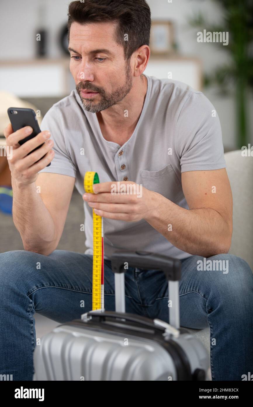 man checking hand luggage size online Stock Photo