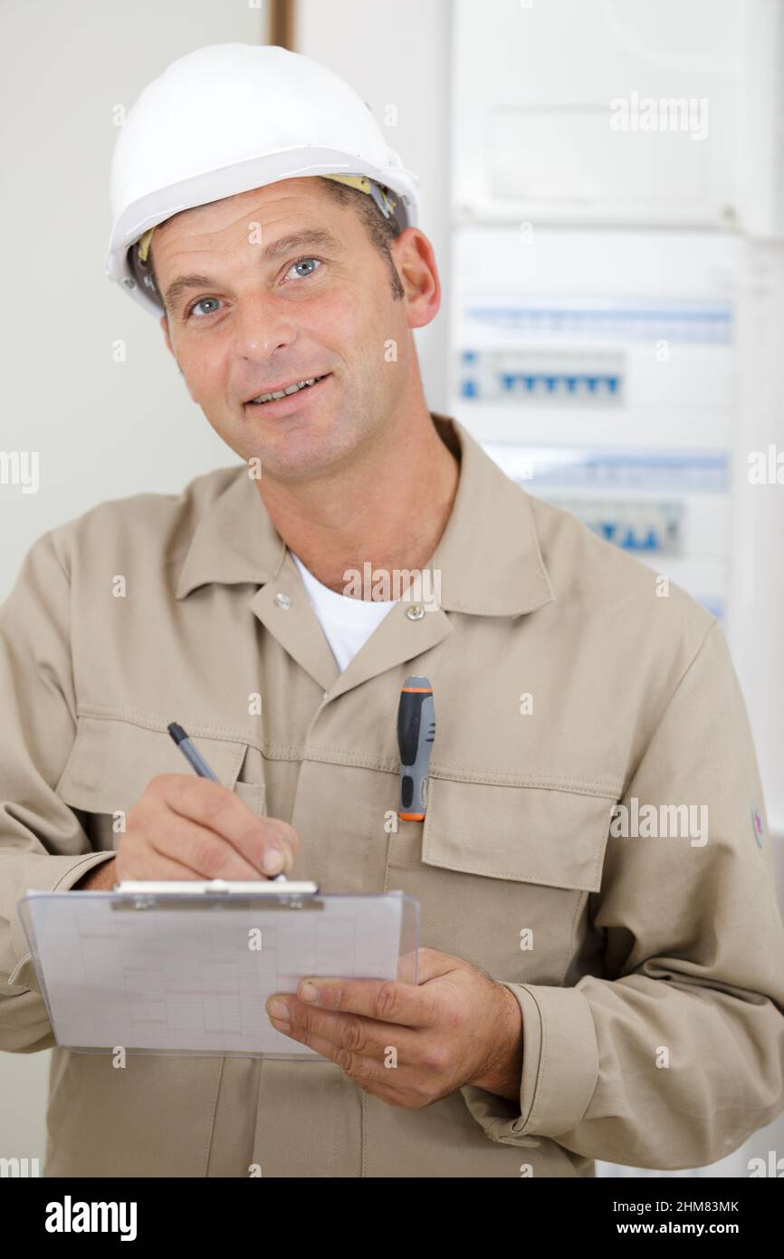 concentrated man builder in building helmet writing on clipboard Stock ...