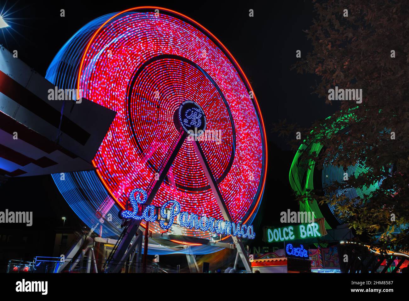 Panoramic wheel running in the dark. Luna park attraction. Long exposure photography. Stock Photo