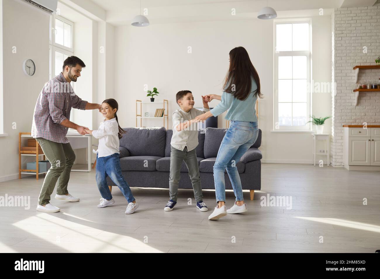 Happy parents and children dancing and having fun in their new house or apartment Stock Photo