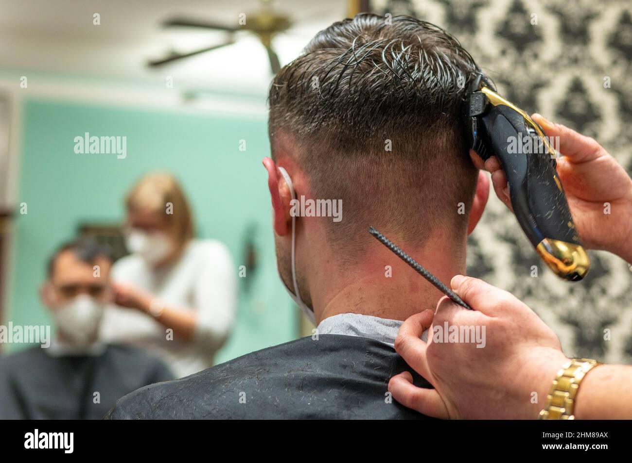 Straubing, Germany. 08th Feb, 2022. A hairdresser shaves a customer's hair.  In Bavaria, body-related services such as hairdressing or nail salons will  once again be available to visitors with a negative Corona