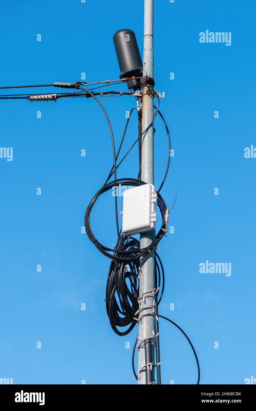 Cable TV grounding box mounted on utility pole against blue sky Stock Photo