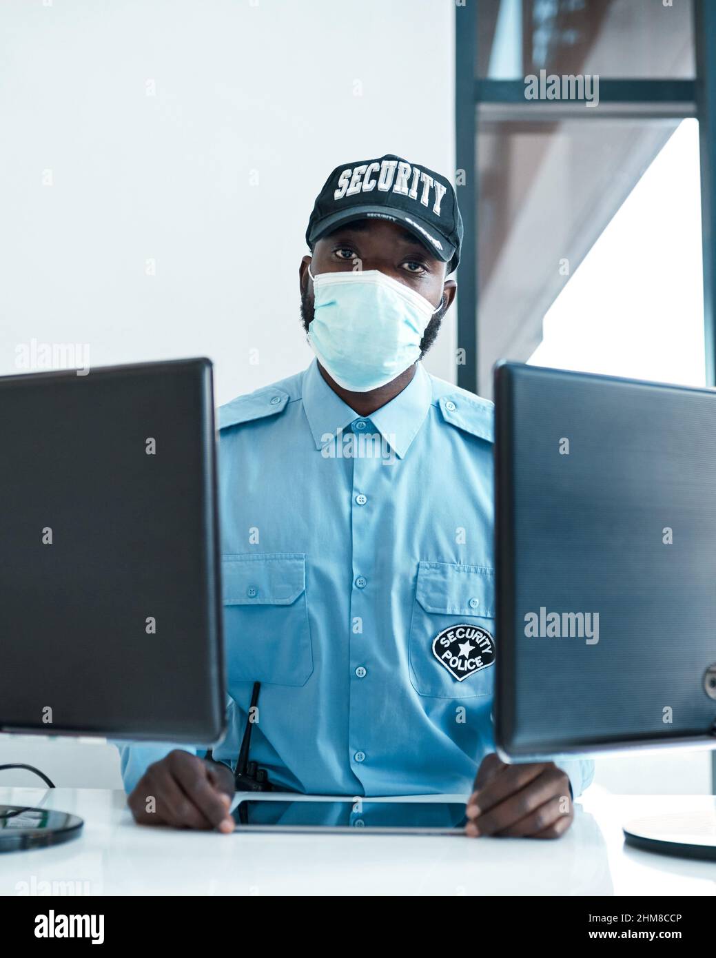 I keep all unwelcome guests out, including viruses. Portrait of a confident masked young security guard on duty at the front desk of an office. Stock Photo