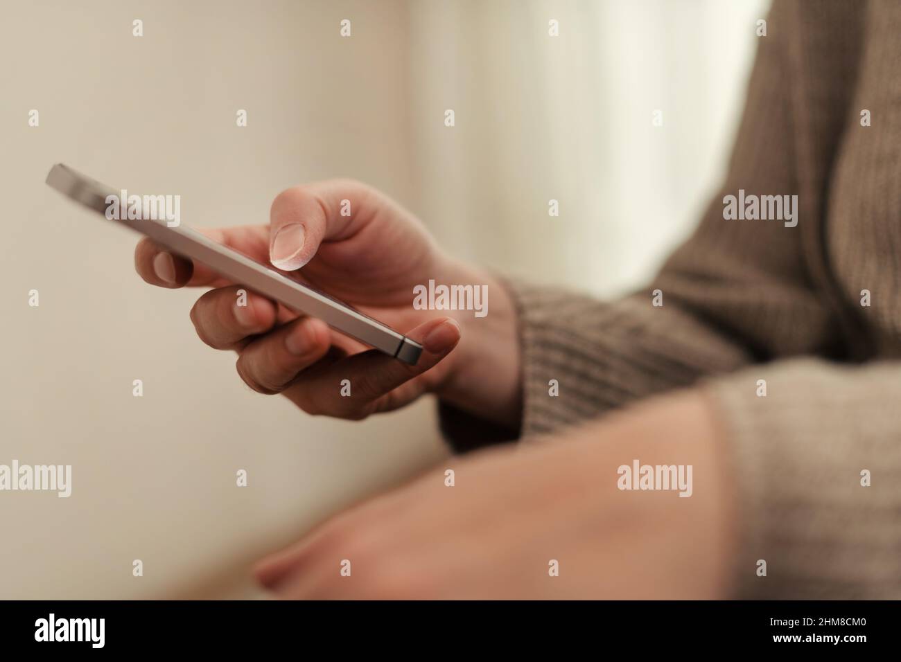 Closeup of female hands using smartphone for communication in living room, selective focus Stock Photo