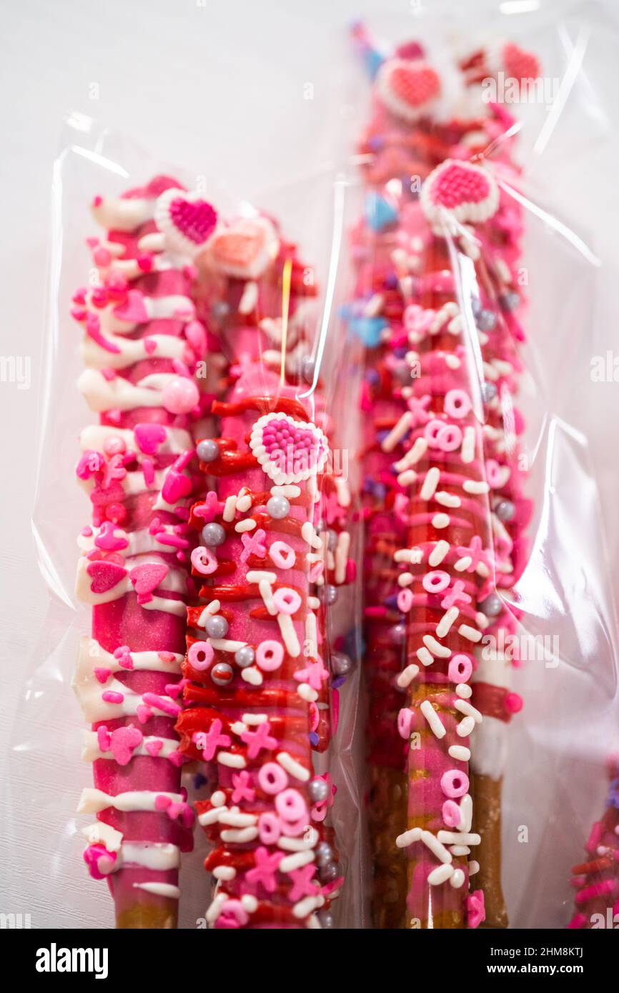 Chocolatecovered pretzel rods decorated with heartshaped sprinkles