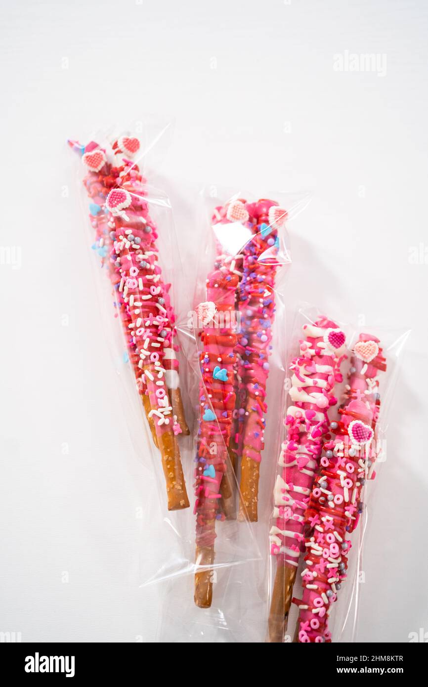 Chocolatecovered pretzel rods decorated with heartshaped sprinkles