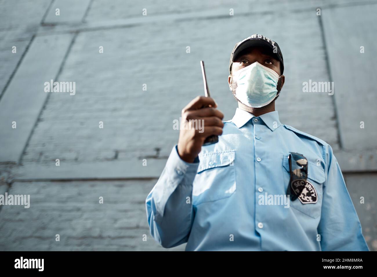 Proactive guarding for your propertys protection. Shot of a masked young security guard using a two way radio while on patrol outdoors. Stock Photo