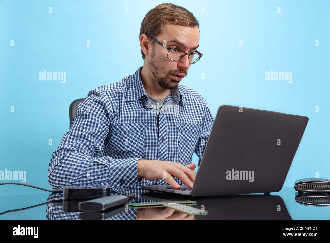 Portrait of man, IT programmer, web developer working on software isolated over blue background Stock Photo