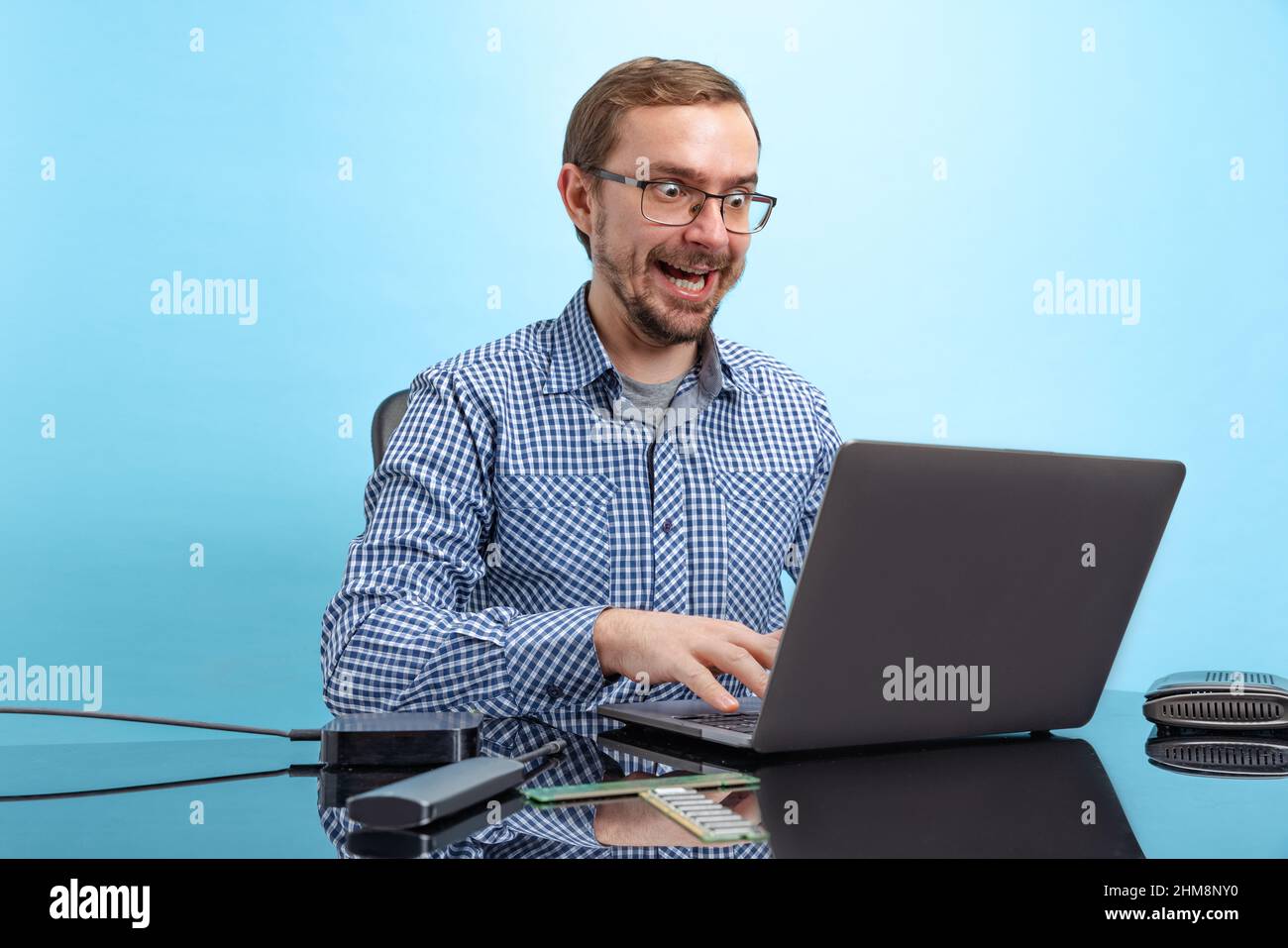 Portrait of man in glasses and checkered shirt, computer geek, programmer isolated over blue background Stock Photo