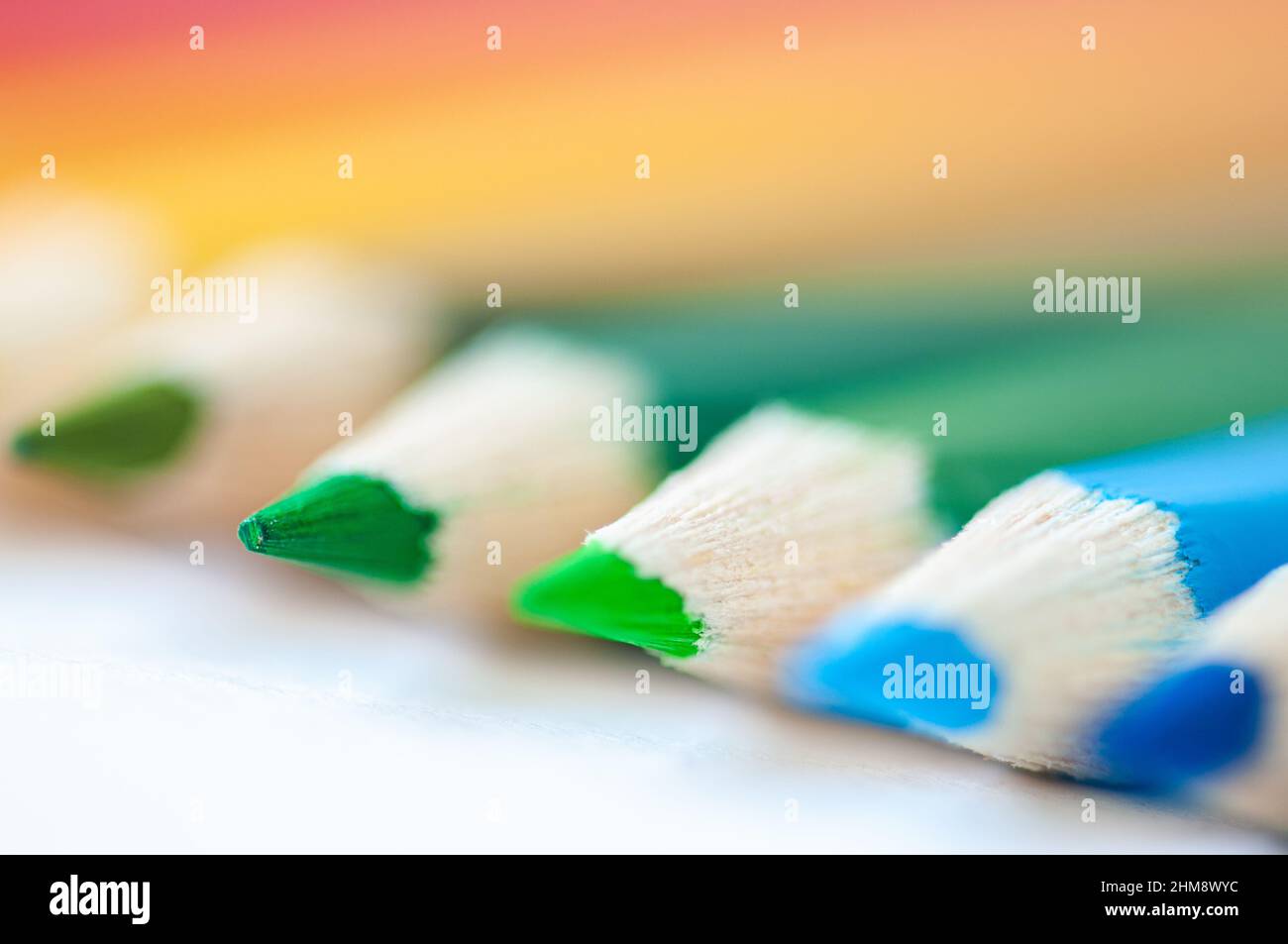 Set of wooden colored pencils- crayons on a white paper. Close up. Selective focus. Stock Photo