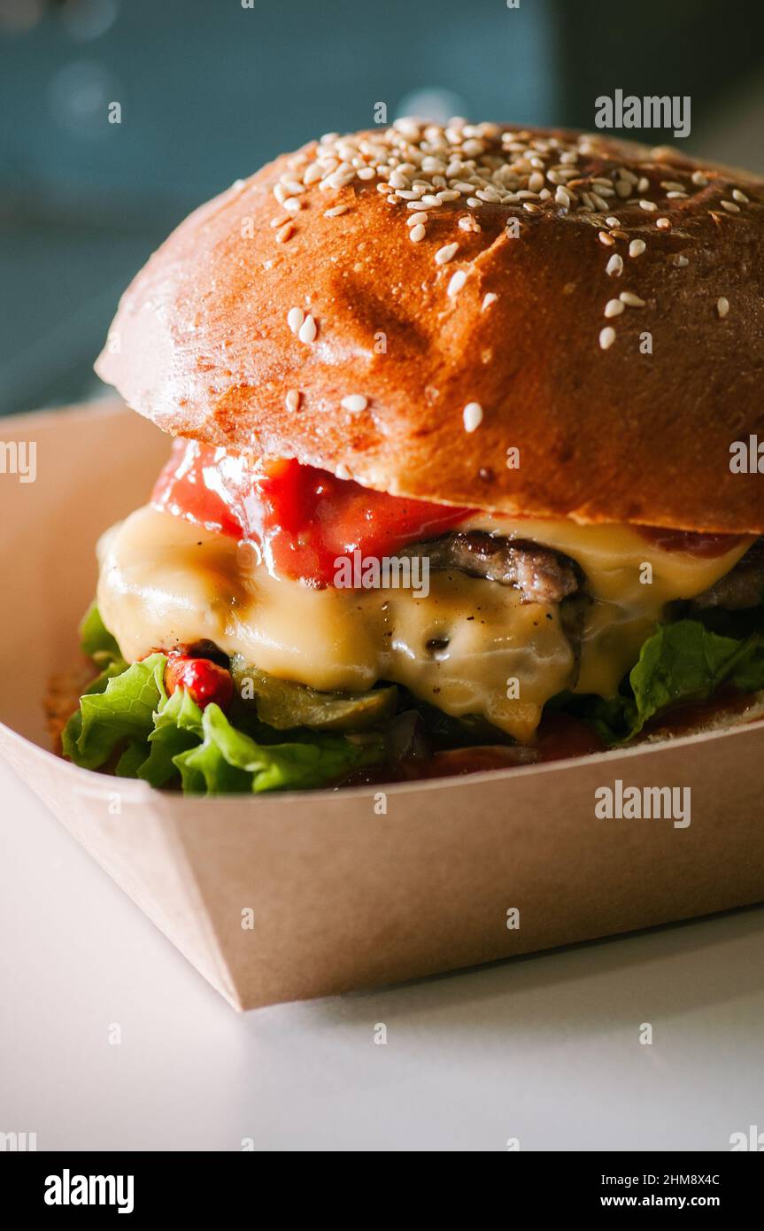 Freshly prepared cheeseburger in a paper box is ready to eat. Food delivery concept Stock Photo
