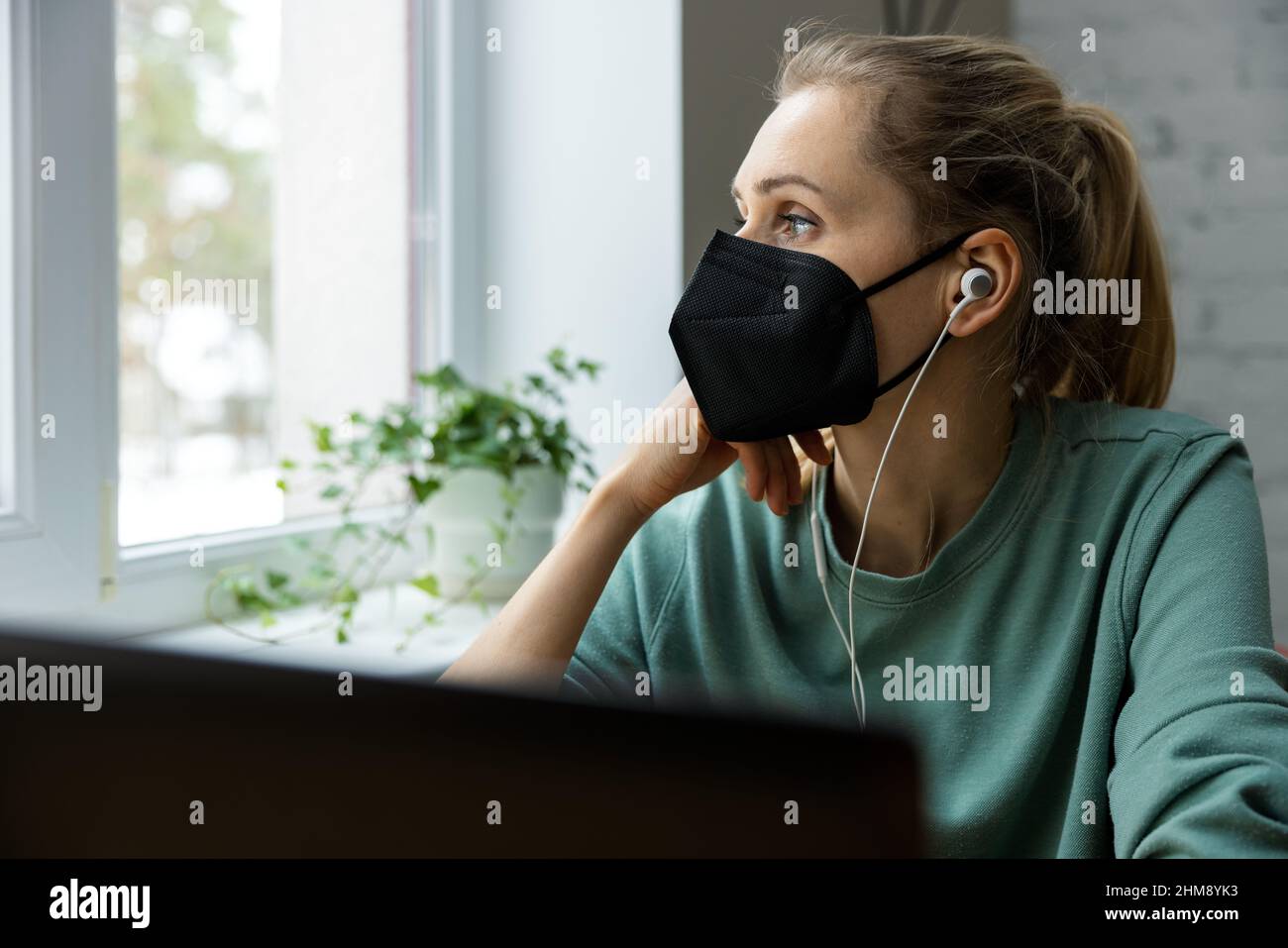 worried depressed woman wearing face mask in office at work and looking out of the window. mental health and burnout concept Stock Photo