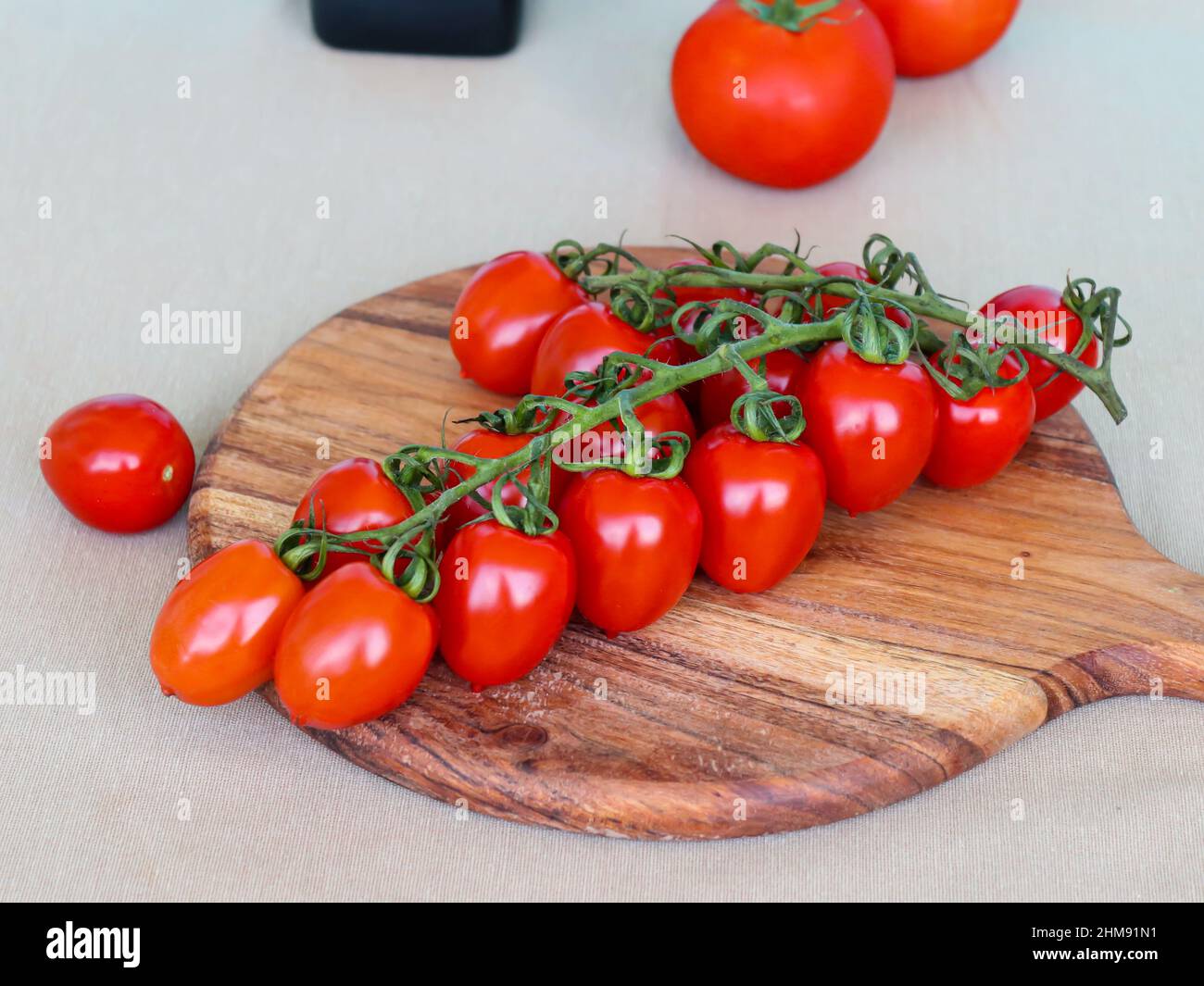 Red cherry tomatoes on wooden cutting board Stock Photo - Alamy