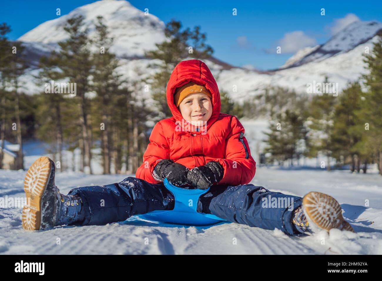 happy and positive little boy enjoying sledding and cold weather ...