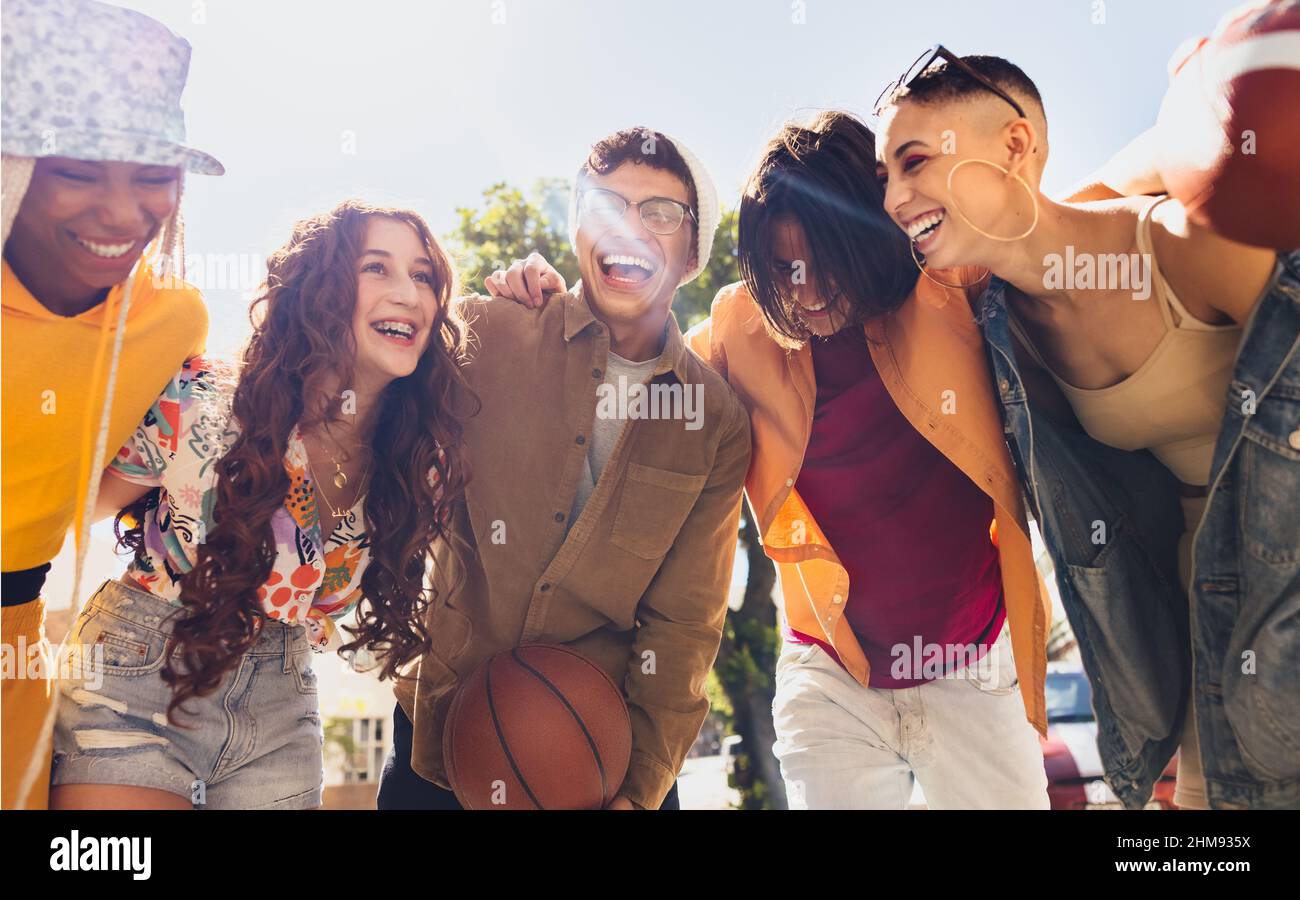 Fun in the sun. Happy group of young friends smiling cheerfully while embracing each other outdoors. Circle of generation z friends having fun togethe Stock Photo