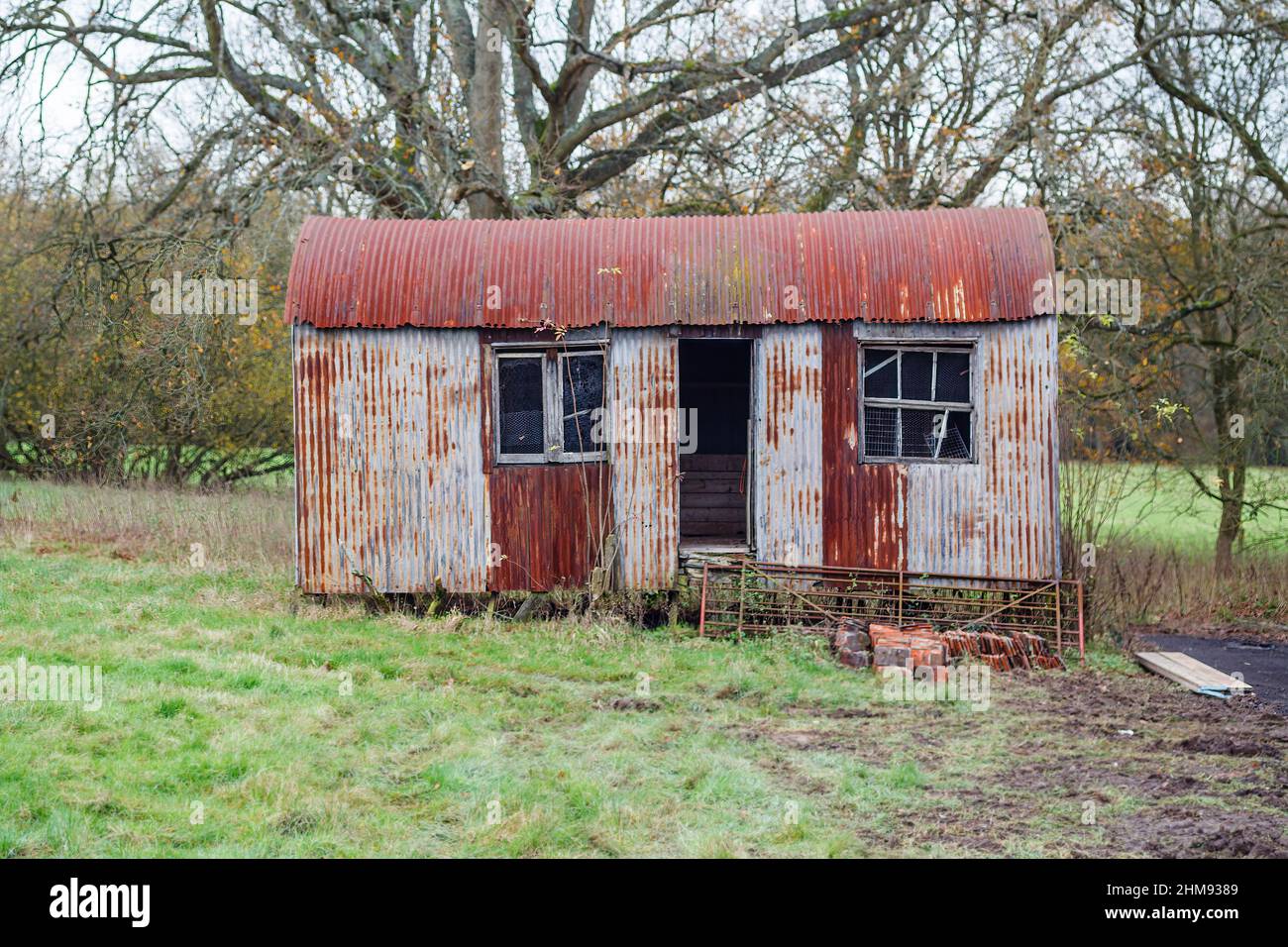 A disused and dilapidated, rusting, corrugated iron shed in a field in Vann, near Ockley, Surrey Stock Photo