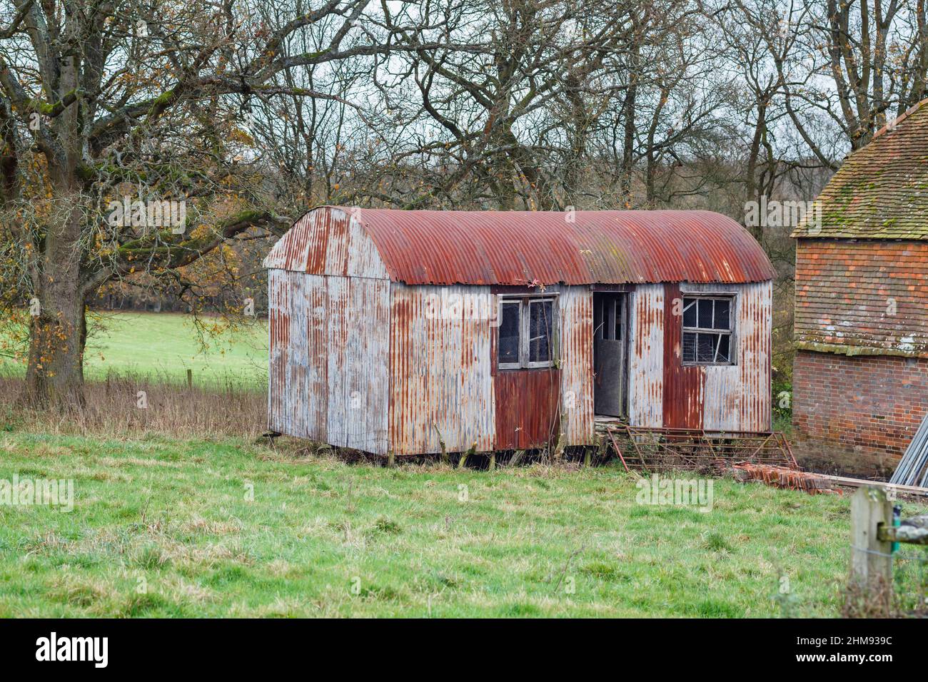 A disused and dilapidated, rusting, corrugated iron shed in a field in Vann, near Ockley, Surrey Stock Photo