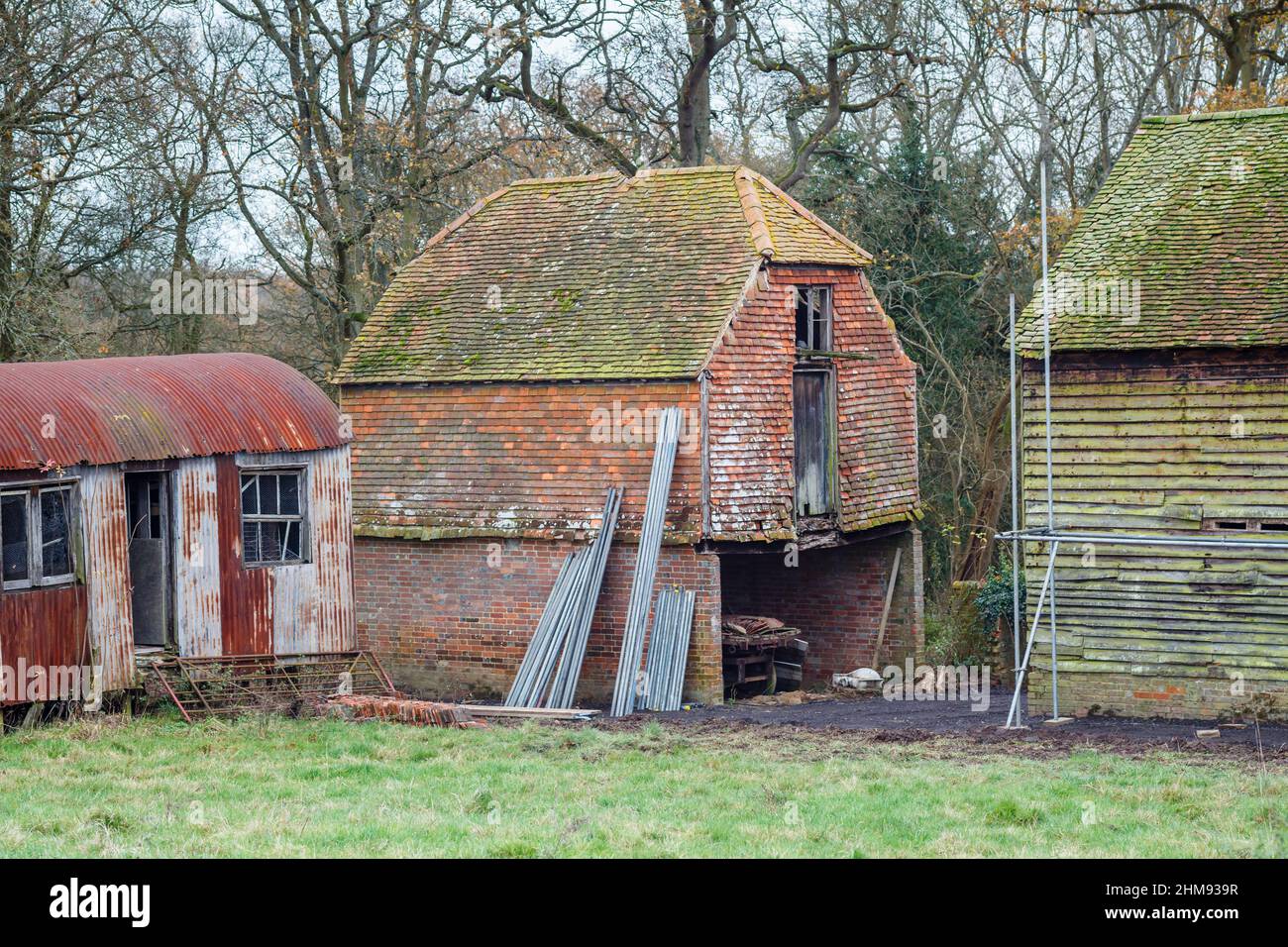 A disused and dilapidated, rusting, corrugated iron shed and agricultural outbuildings in a field in Vann, near Ockley, Surrey Stock Photo