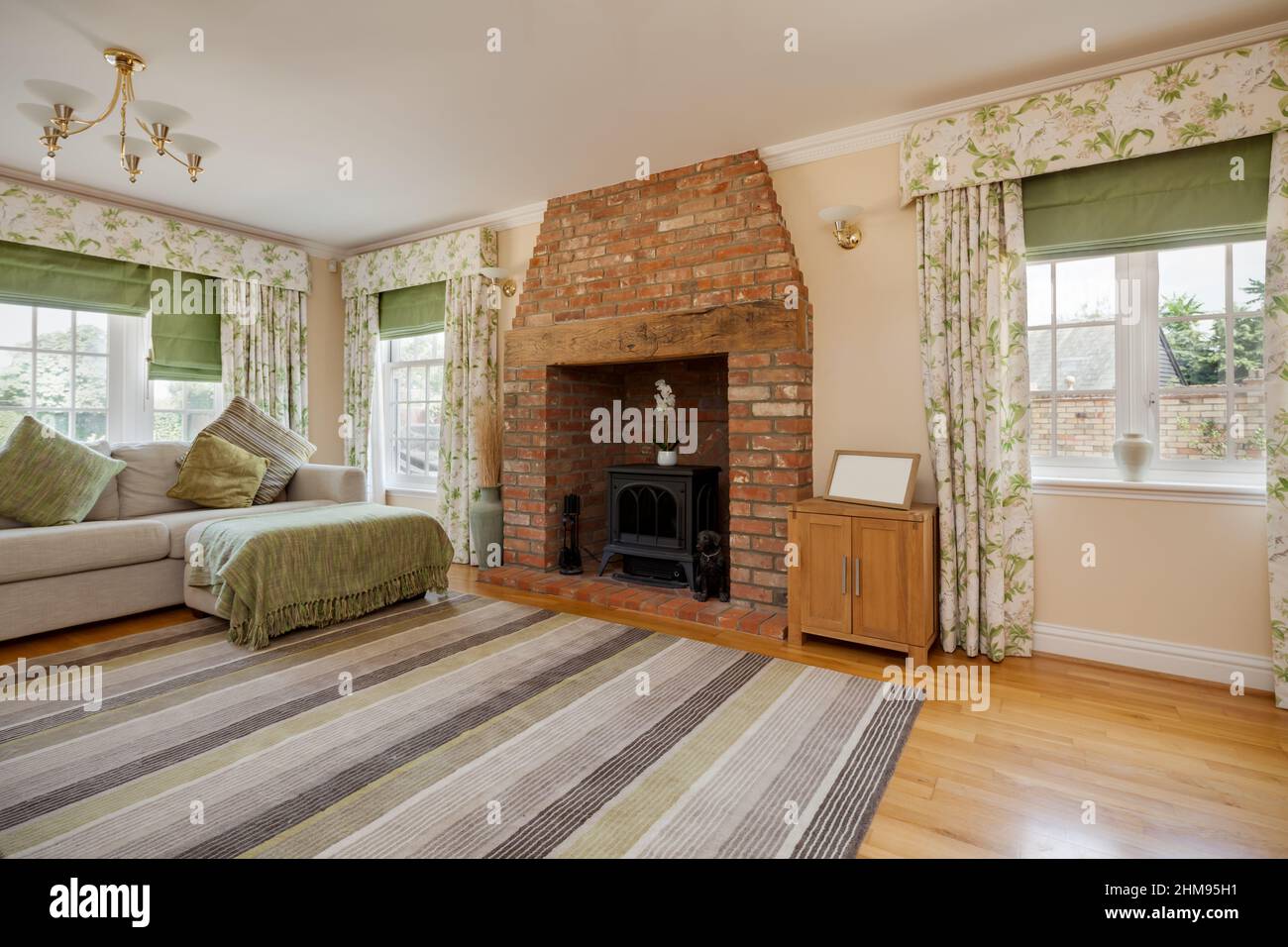 Burrough Green, Suffolk - July 12 2018: Modern luxury living room with heavily patterned rug and inglenook style fireplace in exposed brick, dual aspe Stock Photo