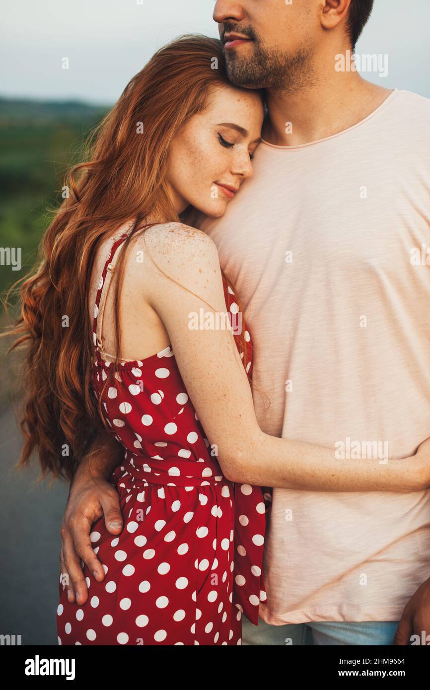 Close-up portrait of a freckled woman hugging her boyfriend while on an outdoor date. Summer vacation. Beautiful summer landscape. Stock Photo