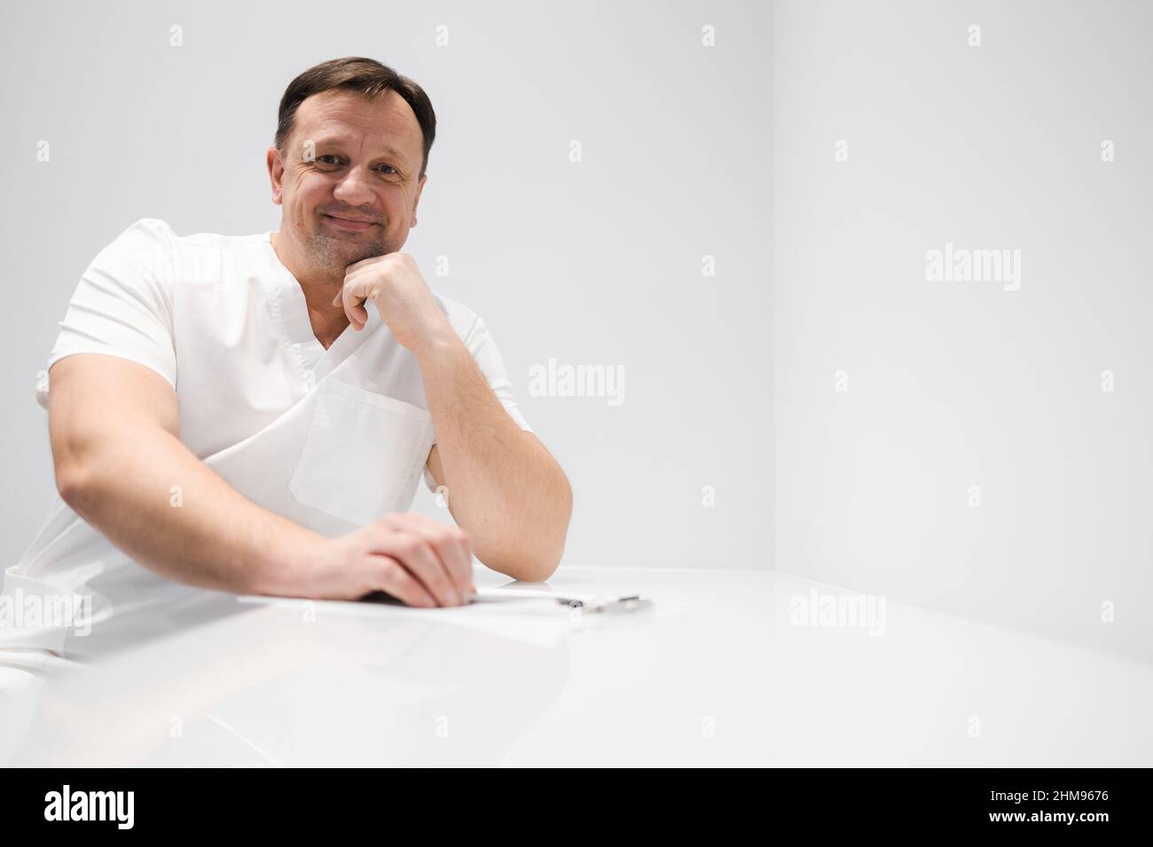 Middle aged male doctor sitting at the table Stock Photo