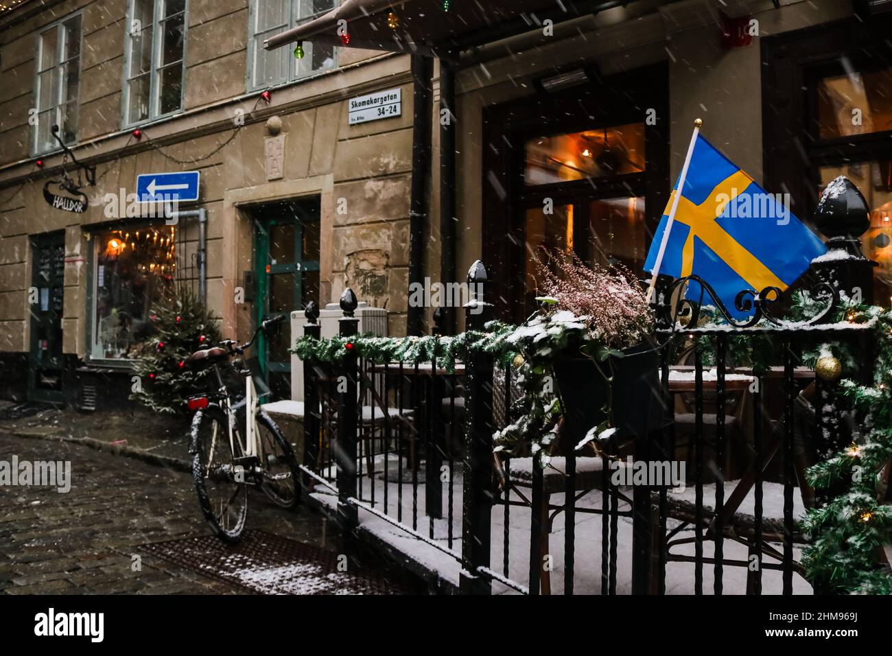 Swedish flag waving in the snow, outside a cafe serving fika in the tourist hotspot 'Gamla Stan', Stockholm, Sweden. High quality photo. Stock Photo