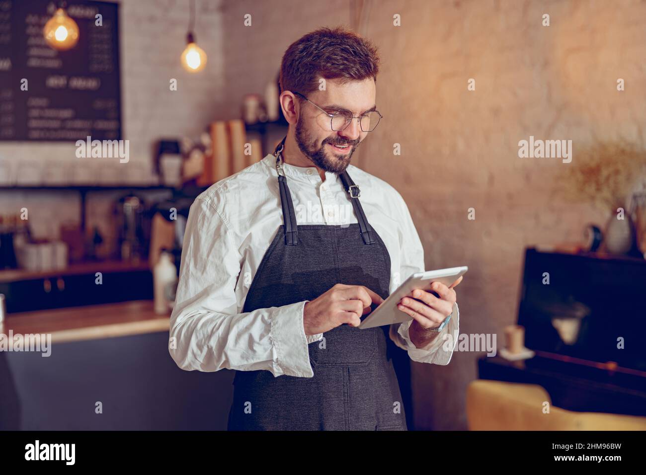 Cheerful male barista using tablet computer in cafe Stock Photo