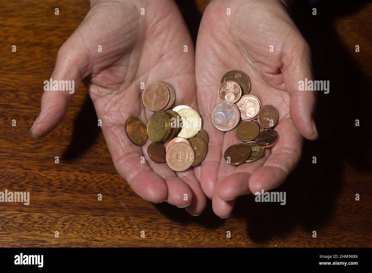 Wrinkled hands of elderly woman holding coins. Stock Photo