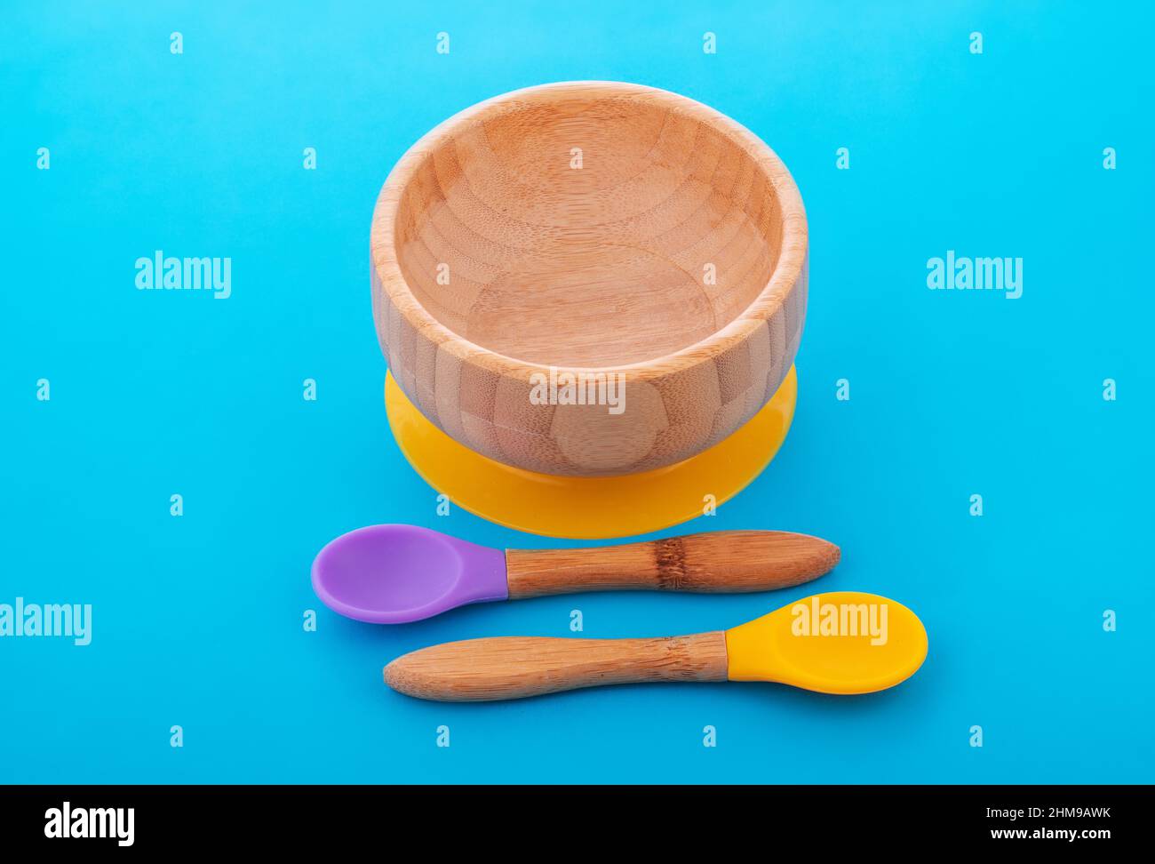 Wooden bowl. Bamboo plate with spoon isolated on blue background Stock Photo