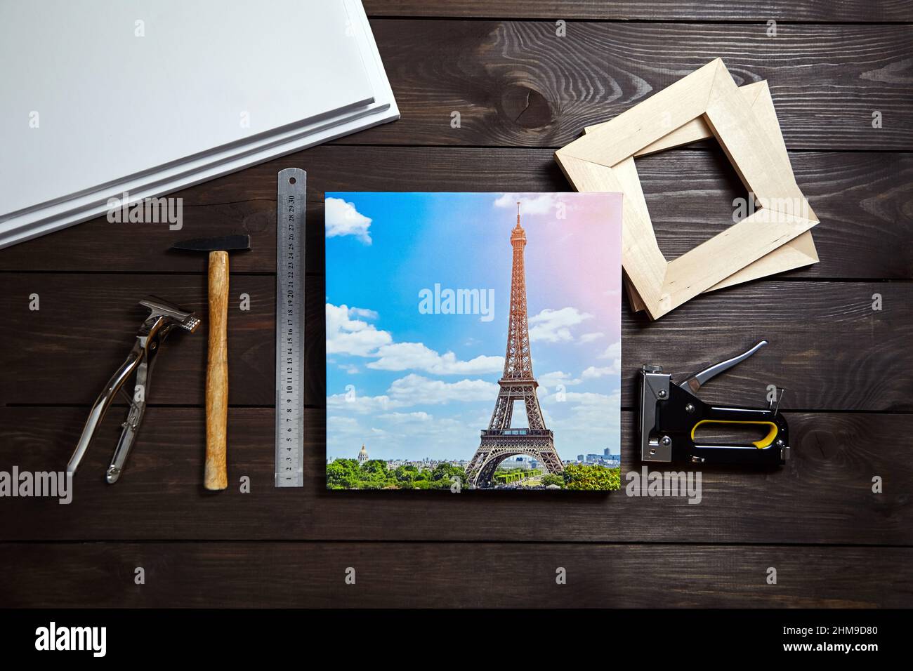 Photography printed on canvas with gallery wrap method. Canvas stretching tools on wooden table. Photo of Eiffel Tower (Paris, France) Stock Photo
