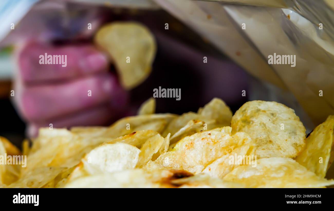 Hand is picking potato chip from bag Stock Photo