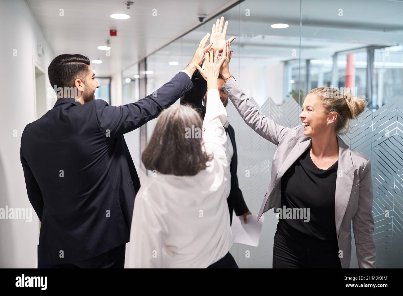 Colleagues Giving High-Five Celebrating Business Success Standing In Office  Stock Photo by ©Milkos 381522740