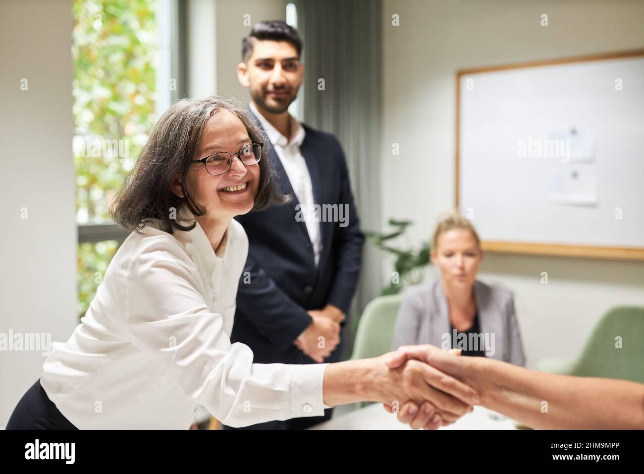 Happy business woman shaking hands in the office as a symbol of greeting and congratulations Stock Photo