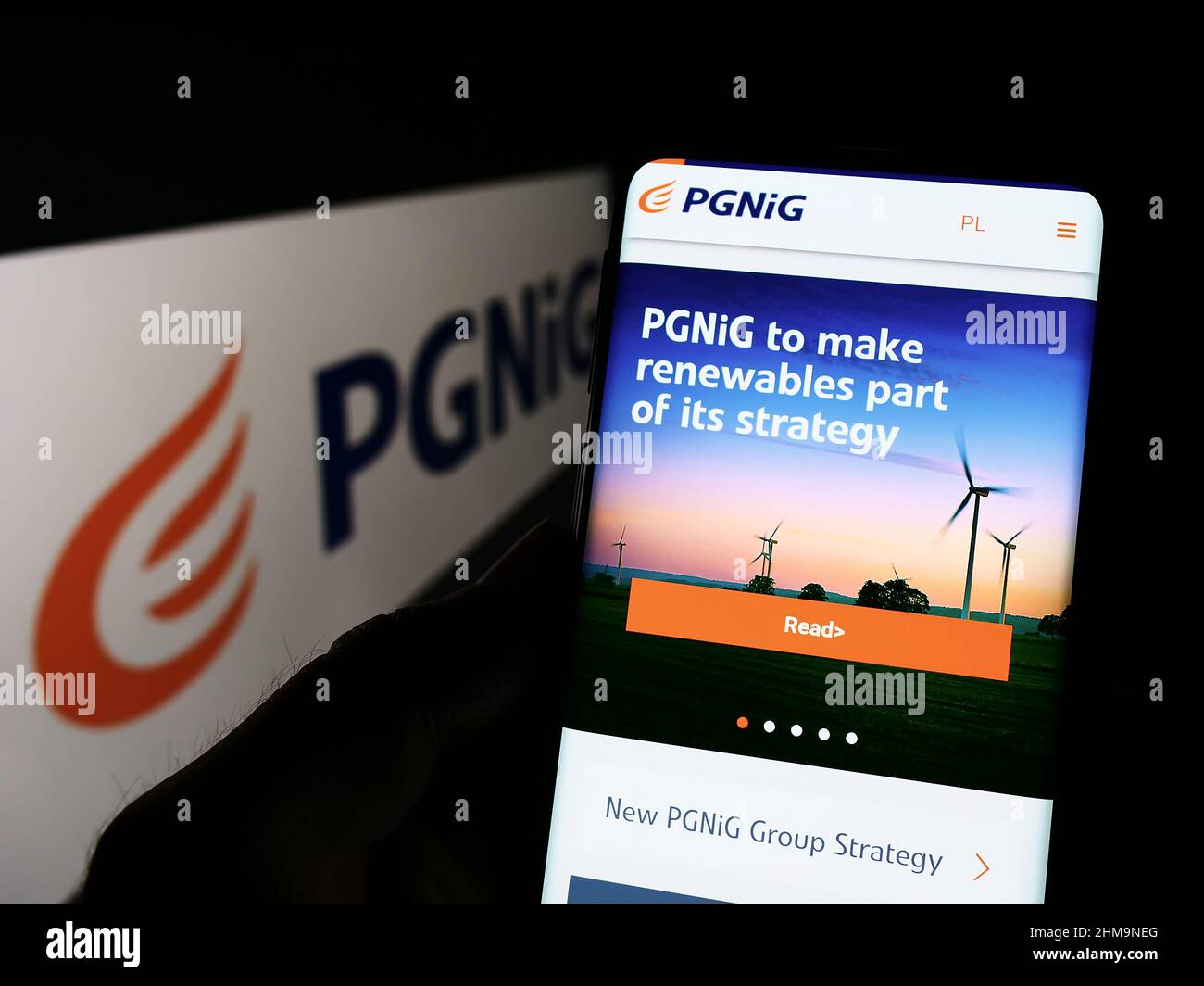 Person holding cellphone with webpage of Polskie Gornictwo Naftowe i Gazownictwo SA (PGNiG) on screen with logo. Focus on center of phone display. Stock Photo