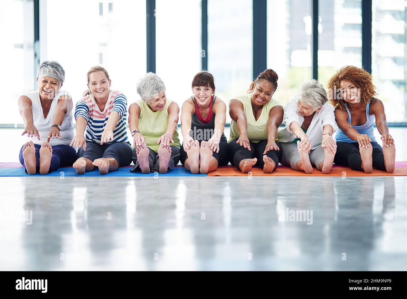 We never forget to warmup. Shot of a group of women warming up indoors. Stock Photo
