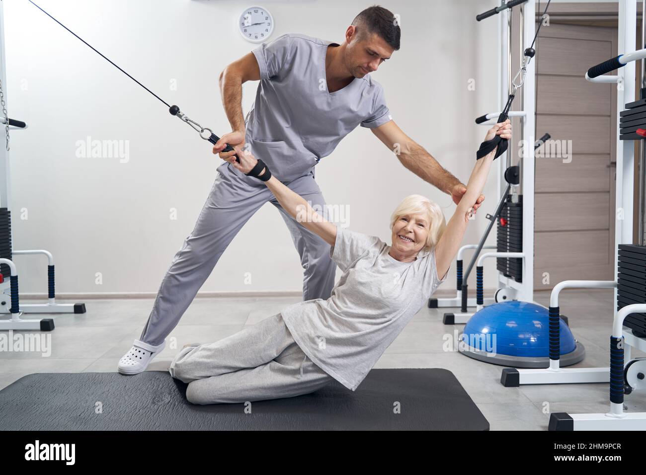 Aging female laying down while holding two cables of machine Stock