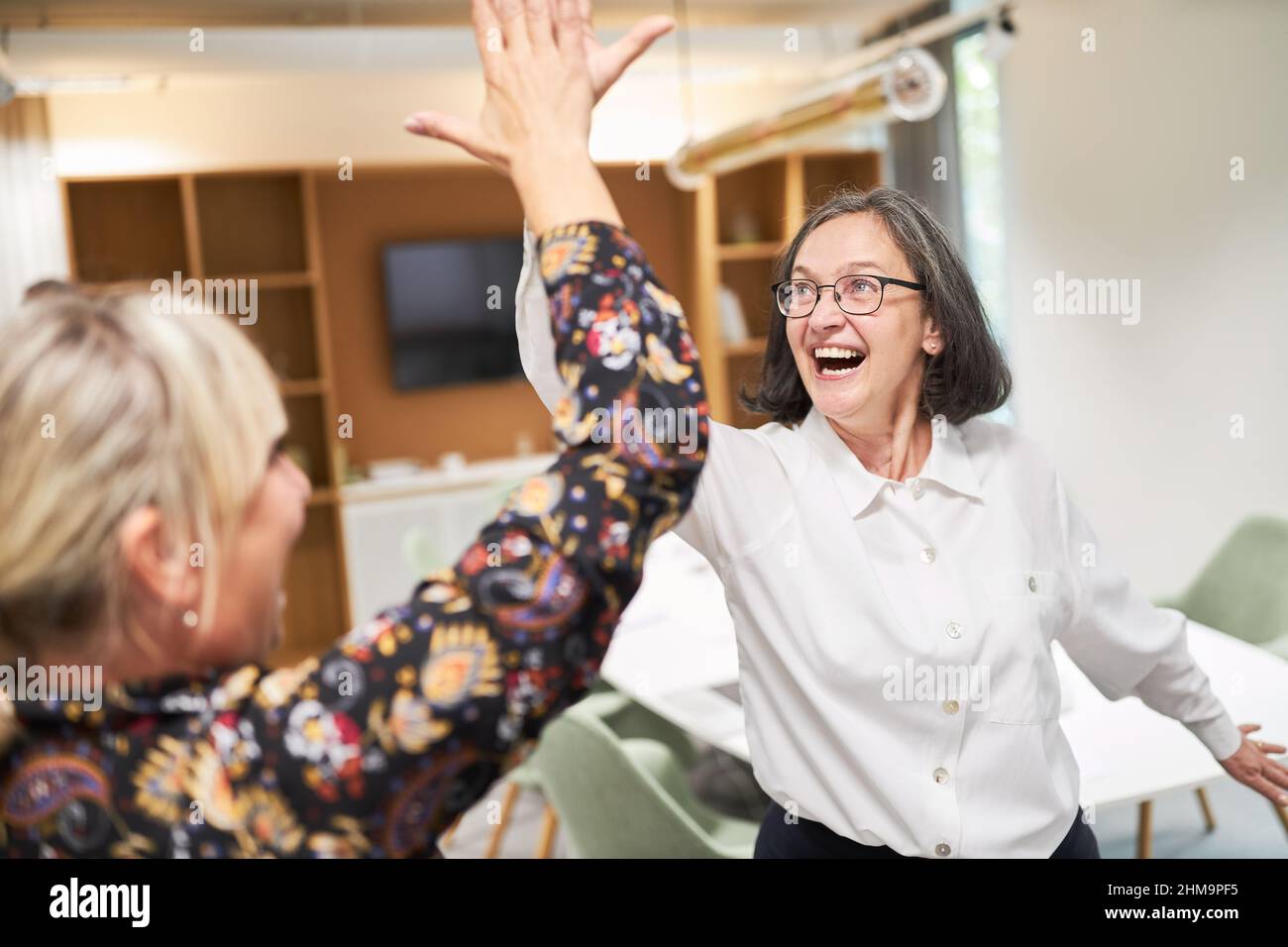 Two happy business women in the office giving high five for motivation ...