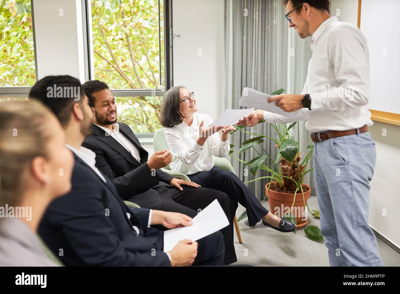 Speaker or teacher distributes teaching material to seminar participants at the VHS or a training course Stock Photo