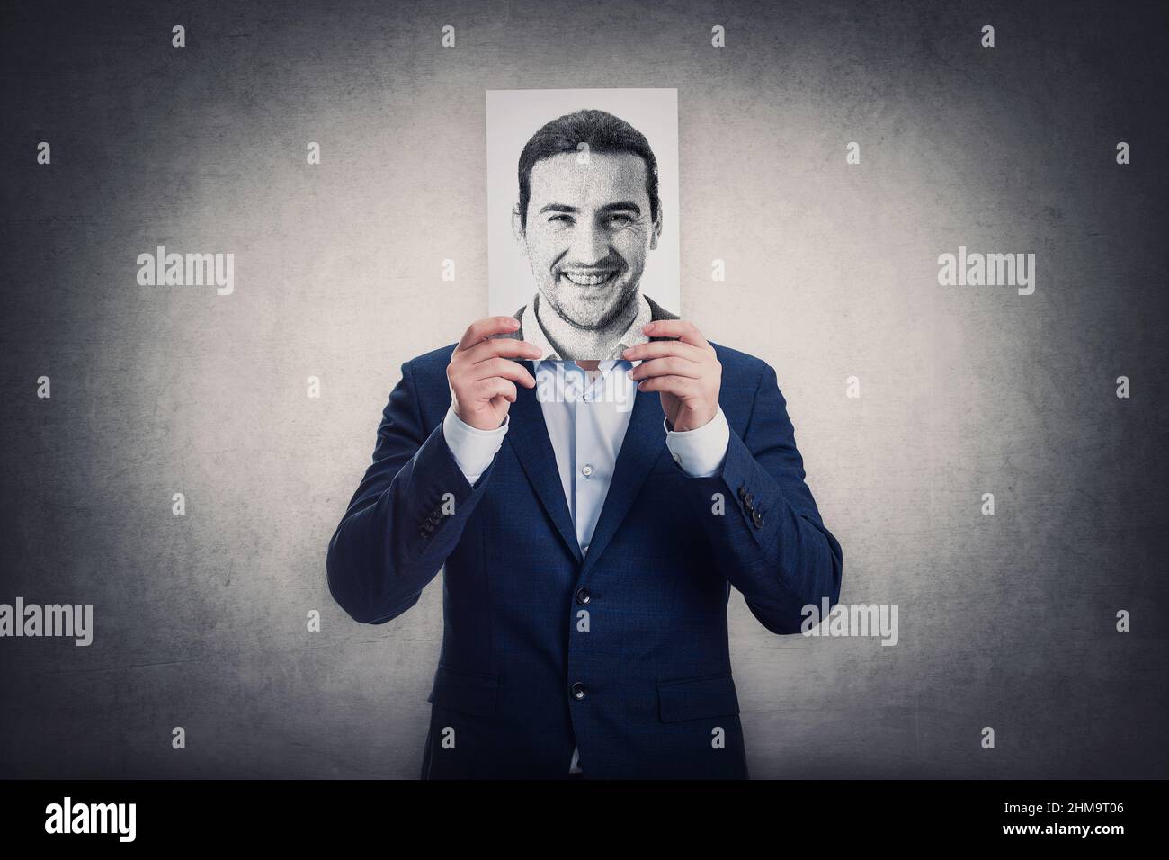 Businessman covers his head with a face print, like a fake mask for hiding real emotions. Sheet with positive face expression. Introvert person, anony Stock Photo