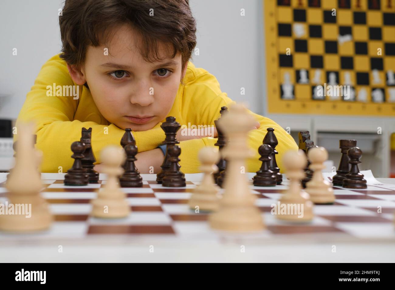 Caucasian boy playing chess. Happy concentrated child behind chess in class or school lesson. Excited clever elementary school kid with board game Stock Photo