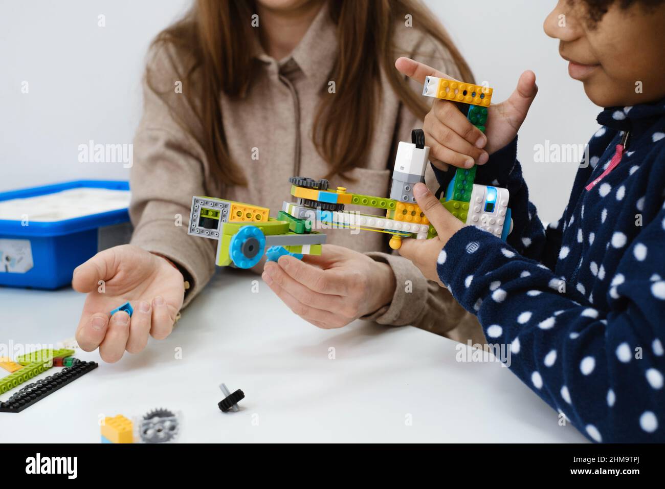 Multiethnic kids at STEM lesson constructing robot in classroom with ...