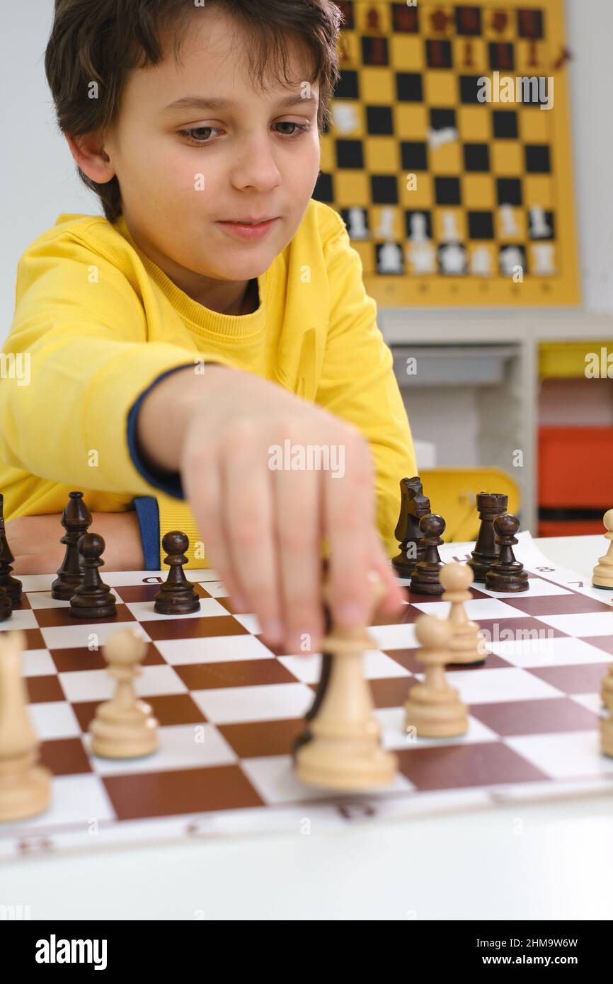Caucasian boy playing chess. Happy concentrated child behind chess in class or school lesson. Excited clever elementary school kid with board game Stock Photo