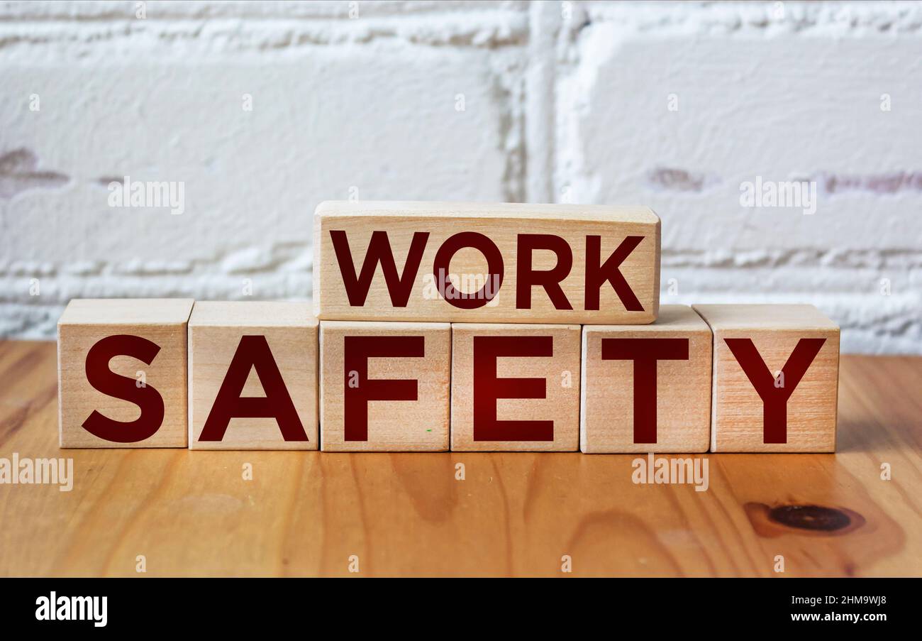WORK SAFETY written on wooden blocks against white brick wall Stock Photo