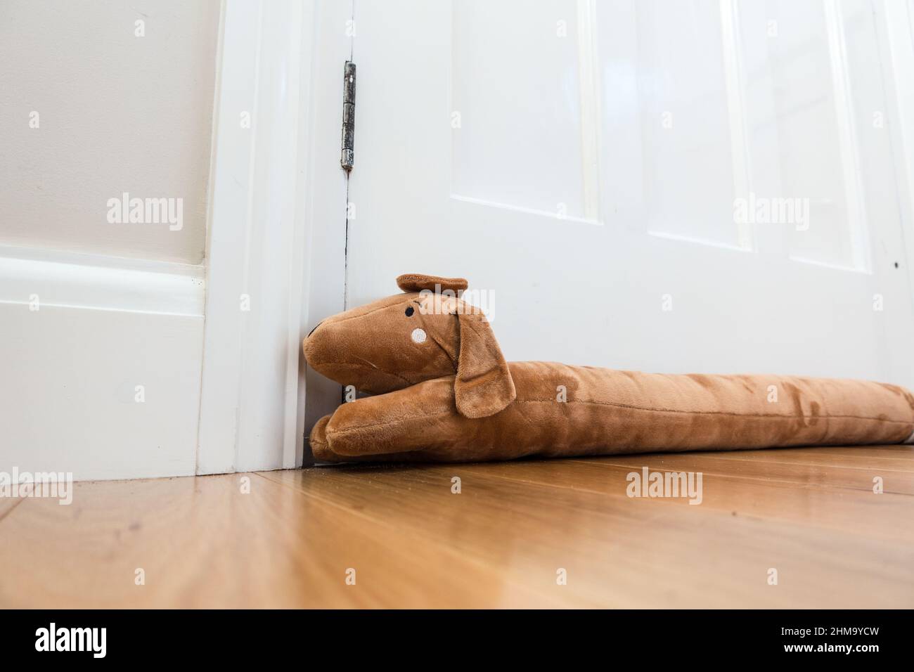Draught Excluder soft toy material covering the gap between door and door frame to reduce escape of heat Stock Photo