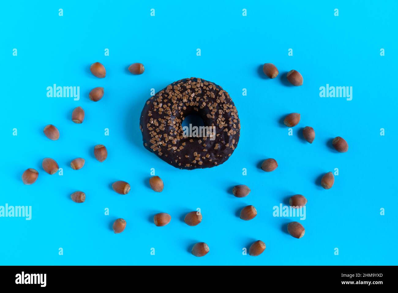 Donut with hazelnuts on a blue background, close up Stock Photo