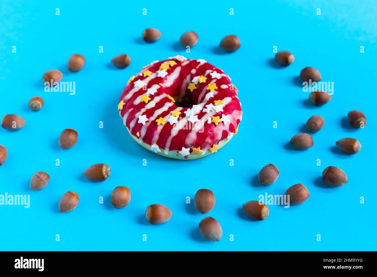 Donut with hazelnuts on a blue background, close up Stock Photo