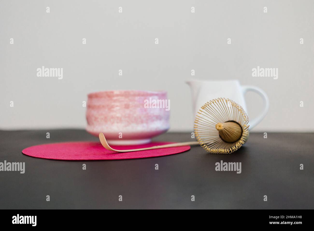 Ceramic bowl and wooden chasen and chashaku on pink round stand on black table at sunlight Stock Photo
