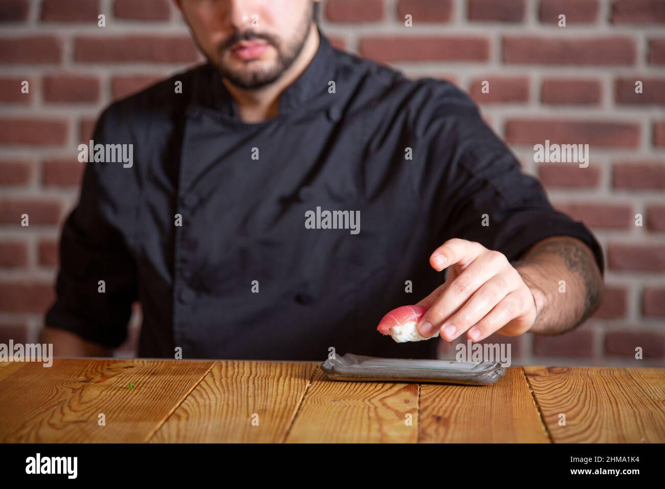 Crop anonymous chef serving fresh sushi with raw tuna on plate on ...