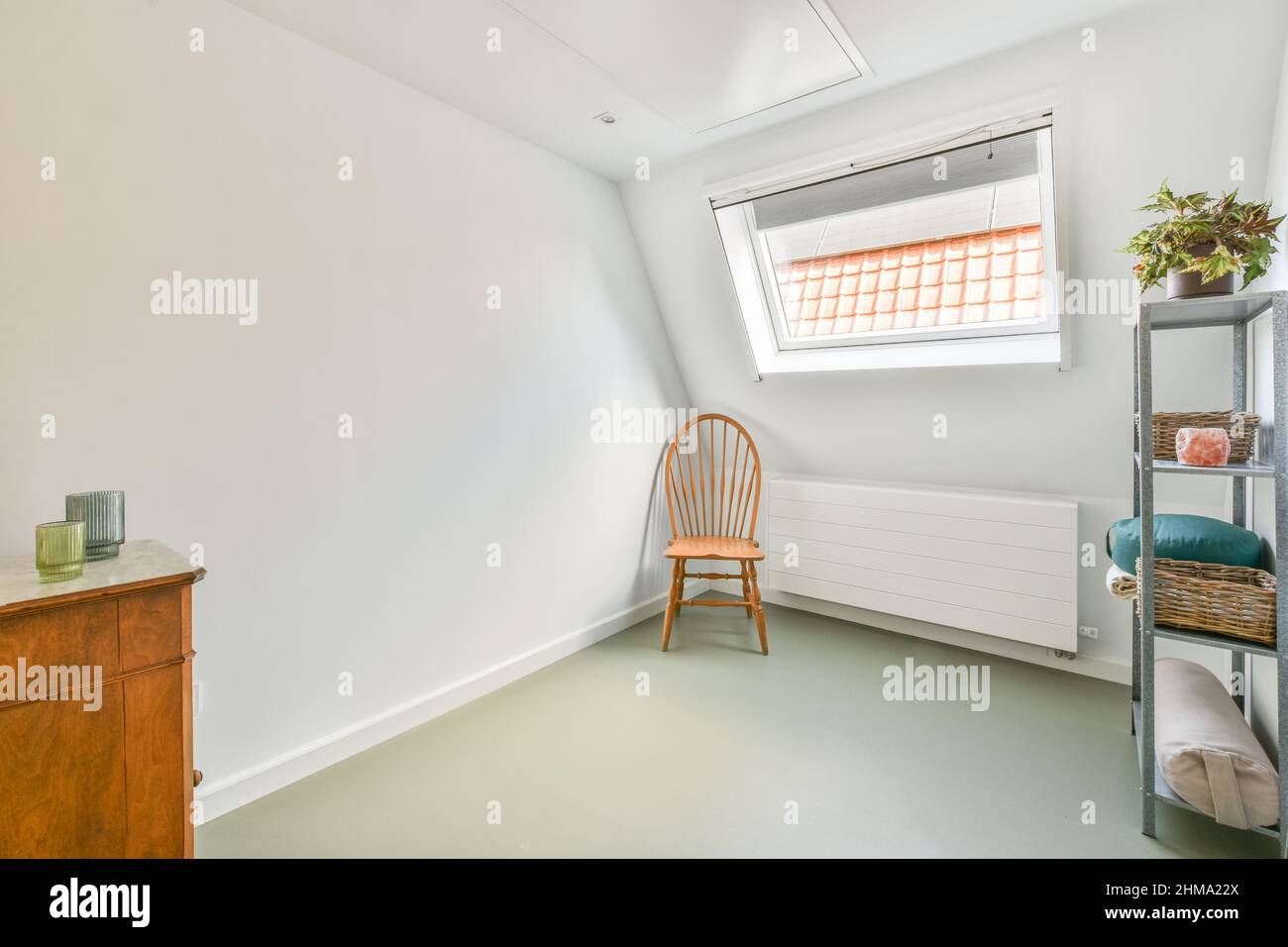 Wooden chair at radiator placed near window in light attic with wicker ...
